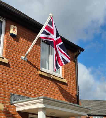 angled flagpole on a wall with a hand sewn Union Jack flag.