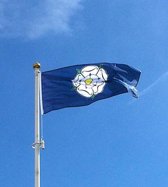 Yorkshire rose flag flying from a flagpole on a sunny day