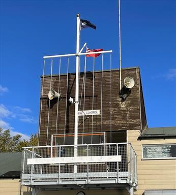 fibreglass flagpole displaying flags from a yard arm and gaff at a sailing club